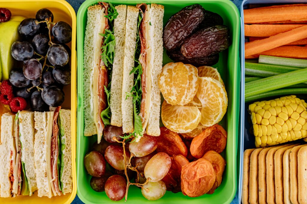 pexels-photo-5852329-5852329 Colorful lunchbox with sandwiches, fresh fruits, and vegetables showcasing nourishing nutrition and balanced healthy eating.