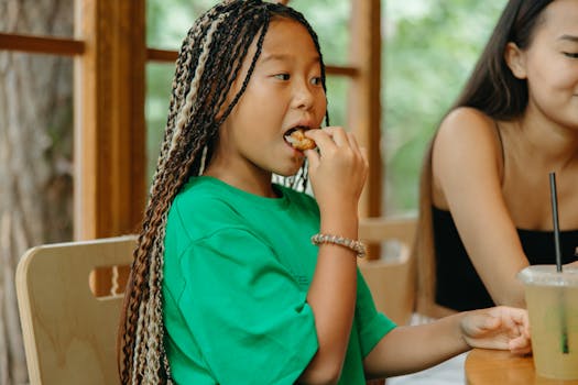 Building Lifelong Health, One Bite at a Time: Just like this child learning to eat mindfully, proper chewing for better digestion is a fundamental habit that can be cultivated at any age. This focused, unhurried approach is the first and most important step toward unlocking the full spectrum of mastication benefits. A close-up of a child demonstrating proper chewing for better digestion, showcasing the mindful and focused eating habits that are foundational to good health.