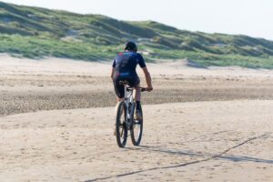 A cyclist in motion on a scenic road, demonstrating the powerful health benefits of exercise like improved cardiovascular endurance and mitochondrial function. Consistent cycling is a highly effective way to achieve the core benefits of exercise, including boosting your cells' energy production and improving blood sugar regulation, as highlighted in recent physiological studies.