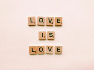 Wooden tiles spell 'Love is Love,' visually representing the inclusive and unifying power of love for all people.