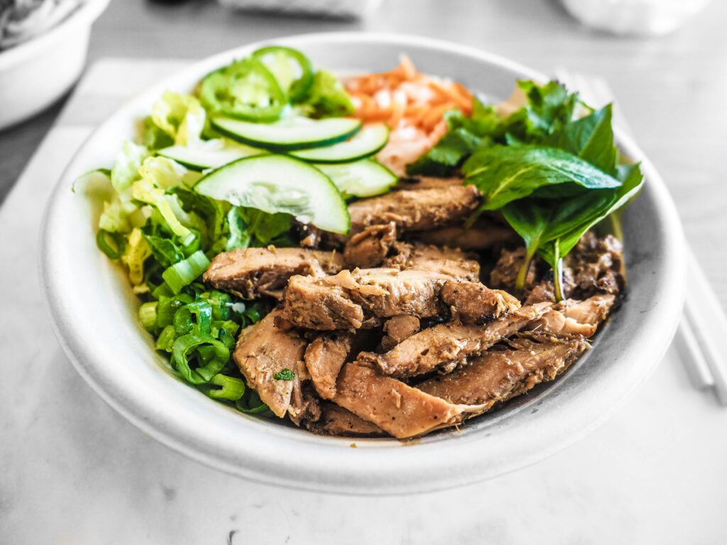 pexels-photo-2059150-2059150 Close-up of a healthy bowl featuring grilled chicken, fresh vegetables, and herbs, perfect for a nutritious meal.