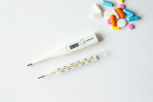 Thermometers and colorful pills on white background — practical tools for interpreting symptoms at home.