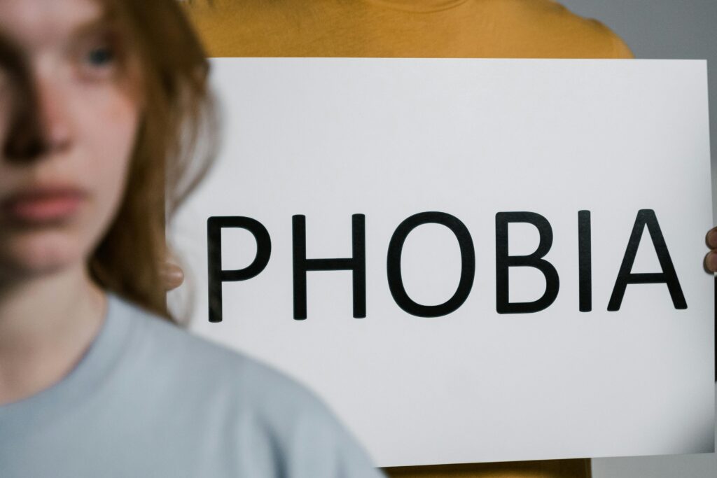 A person holding a sign that says 'Phobia', visually explaining the concept of how fear affects health and mental wellbeing.