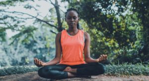 Woman practicing deep breathing meditation outdoors in a lush green setting to enhance relaxation, mindfulness, and digestive health.peacefully outdoors in a lush green setting, promoting relaxation and mindfulness. Woman meditating outdoors in a lush green environment, illustrating deep breathing benefits for relaxation, mindfulness, better digestion, and overall health