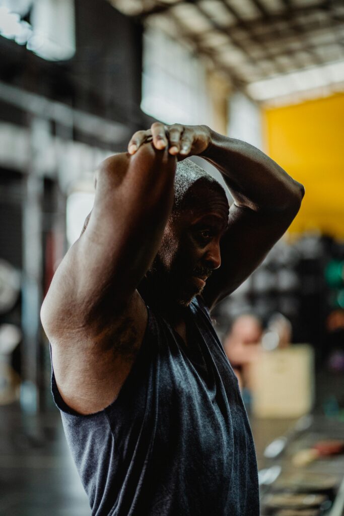 A focused athlete performing a stretch in an industrial gym setting. Deep squat hold position for hip and knee joint mobility exercises in functional training.