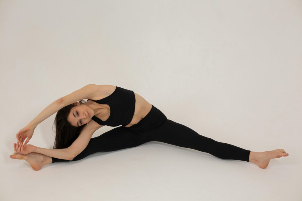 Advanced Flexibility for Core Strength: This impressive split demonstrates the flexibility that enhances exercises like the leg-over-head stretch, a powerful movement to strengthen stomach muscles and stimulate your digestive organs through deep abdominal engagement and improved circulation A flexible young woman performing a full split, demonstrating the advanced flexibility required for exercises like the leg-over-head stretch that help strengthen stomach muscles.