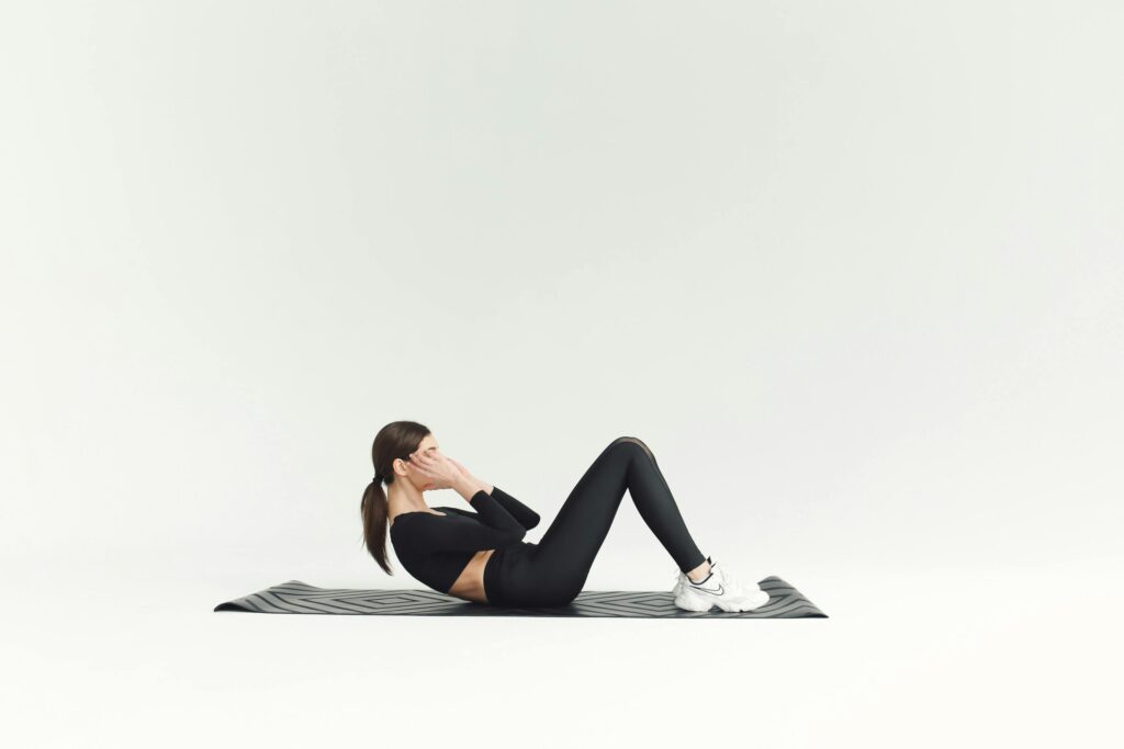 Mastering the Seated Sit-Up: This fundamental core exercise actively engages your abdominal muscles, stimulating the blood flow and involuntary contractions necessary for efficient digestion. Regularly performing seated sit-ups helps strengthen stomach muscles, supporting your body's natural digestive process and enhancing nutrient absorption. A woman in activewear performing a seated sit-up on a yoga mat, demonstrating a key exercise to strengthen stomach muscles and aid digestion.