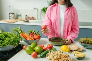 Fresh, vibrant vegetables like tomatoes, peppers, and leafy greens are powerful allies for natural indigestion relief, providing gentle, easy-to-digest nutrients that soothe the stomach. Woman selecting a fresh tomato amidst a variety of colorful vegetables, representing the natural indigestion relief found in a plant-based diet.